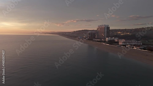 Aerial drone video of the Adriatic Sea at sunrise off Porto Potenza, Italy. Peaceful flyby capturing calm waters, golden reflections, and serene coastal beauty.