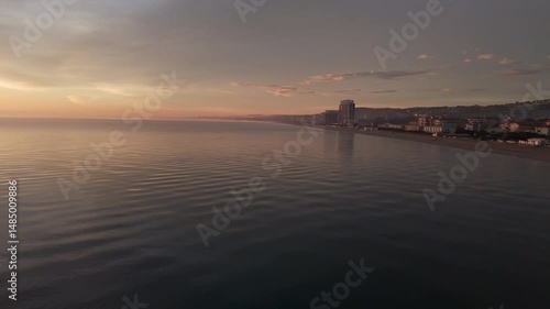 Aerial drone video of the Adriatic Sea at sunrise off Porto Potenza, Italy. Peaceful flyby capturing calm waters, golden reflections, and serene coastal beauty.