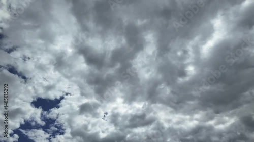 a time-lapse, low angle view, of a stormy sky with evolving darkening clouds under a deep blue sky.