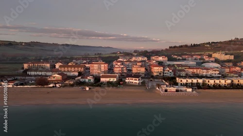 Aerial drone video of the Adriatic Sea at sunrise off Porto Potenza, Italy. Peaceful flyby capturing calm waters, golden reflections, and serene coastal beauty.