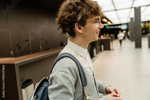 Εκτύπωση καμβά A young White male office worker smiles while standing in a modern lobby of a business center