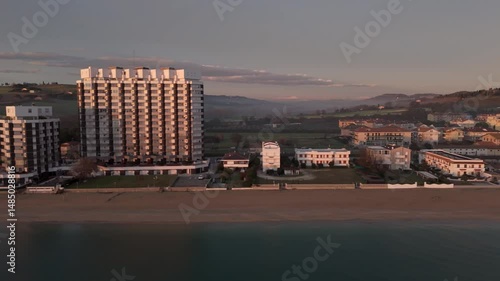 Aerial drone video of the Adriatic Sea at sunrise off Porto Potenza, Italy. Peaceful flyby capturing calm waters, golden reflections, and serene coastal beauty.