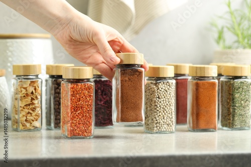 Fototapeta Naklejka Na Ścianę i Meble -  Woman taking jar with nutmeg powder indoors, closeup