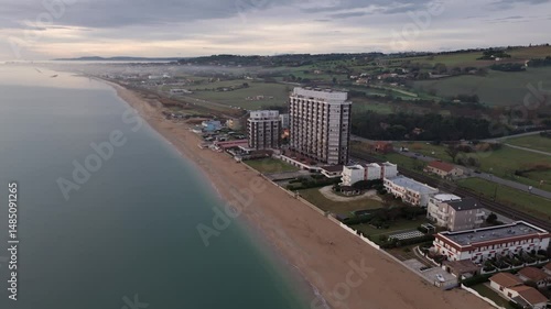 Aerial drone video of the Adriatic Sea at sunrise off Porto Potenza, Italy. Peaceful flyby capturing calm waters, golden reflections, and serene coastal beauty.
