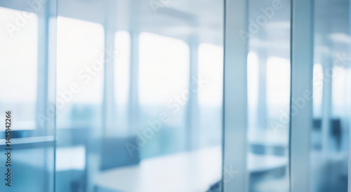 Blurred office interior view through glass partitions featuring chairs and tables.