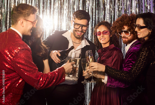 Fotografie Friends in nightclub, holiday colleagues bottle pouring champagne, people wearin