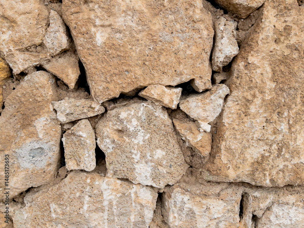 Fototapeta premium Weathered stone wall texture with cracked cement details