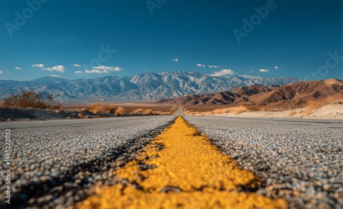 Vast Desert Highway Stretching Towards Majestic Mountains Under a Clear Blue Sky