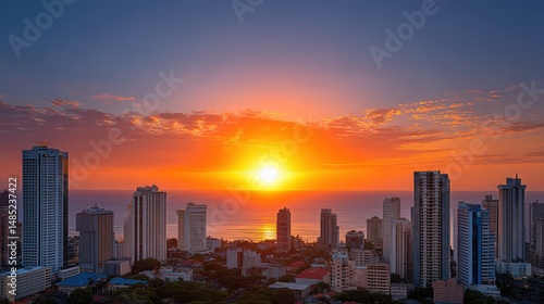 Urban skyline illuminated by vibrant sunset casting golden hues over the ocean with high-rise buildings standing against a dramatic sky creating a breathtaking cityscape