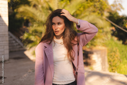 Photo of amazing pretty long wave brunette hair lady flirty fixing hair spending weekend time walking outside wear pink blazer and white long sleeves t-shirt. 