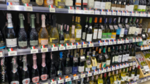 blurred image of wine bottled on the shelf in supermarket. grocery store display wine and liquor defocus, no people.