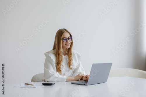 Woman working on laptop at a bright and minimalistic home office during daytime