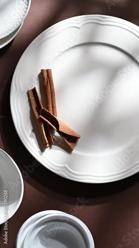 White ceramic dessert plates with cinnamon on brown background. Food concept with space for text
