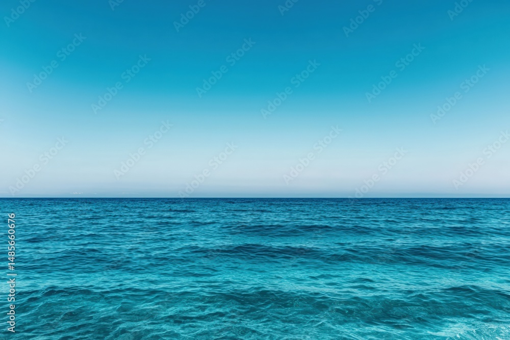 Obraz premium Calm turquoise ocean reflecting pristine blue sky on sunny day