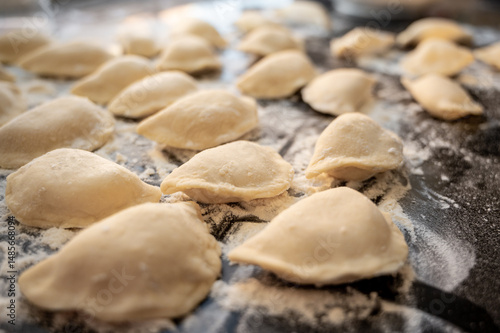Raw varenyky on a black countertop, top view. The process of making Ukrainian varenyky with cottage cheese.