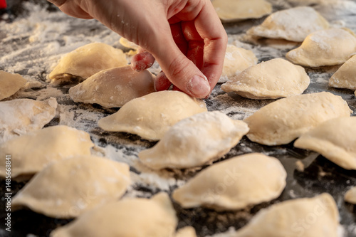 Raw varenyky on a black countertop, top view. The process of making Ukrainian varenyky with cottage cheese.