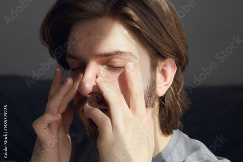 Wallpaper Mural A young man with long hair can apply moisturizer to his face while at home Torontodigital.ca