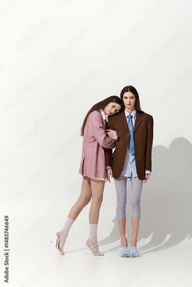 Stylish twin sisters share a tender moment wearing unique fashion ensembles indoors Stylish twin sisters share a tender moment wearing unique fashion ensembles indoors