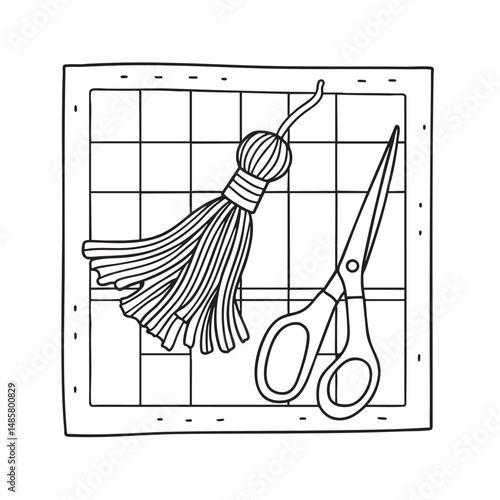 A tassel lying beside a pair of scissors on a craft mat