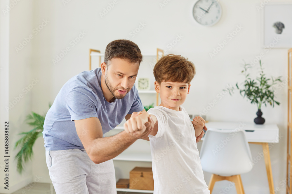 Fototapeta premium Portrait of a father and son engaged in martial arts training together at home. They practice fighting techniques, bonding through exercise and building strength during active workout.