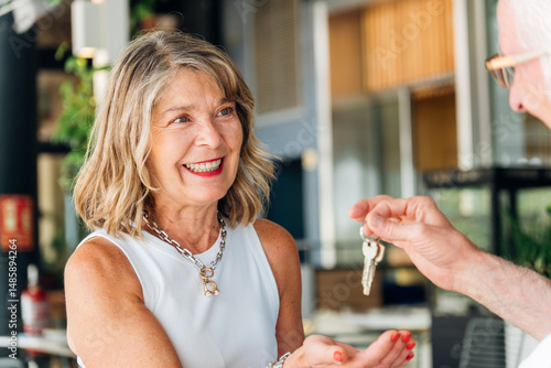 Tableau sur toile Mature female homeowner smiling, accepting property keys from realtor after comp