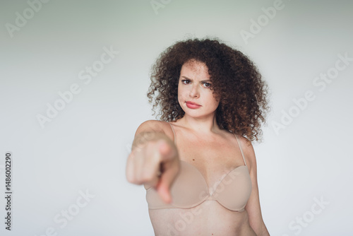 Slika na platnu Confident young woman with curly hair pointing confidently with a stern gaze aga
