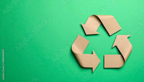 Recycling symbol cut out of kraft paper on vibrant green background, representing sustainability and eco friendliness. This evokes sense of responsibility towards environment
