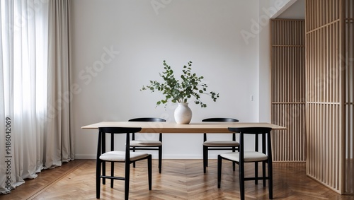 A dining room with a wooden table chairs and a vase of greenery in a minimalist styled interior space