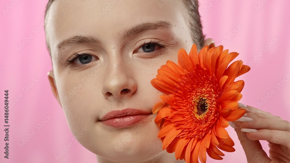 Young Woman with Bright Orange Flower on Vibrant Background Young Woman with Bright Orange Flower on Vibrant Background