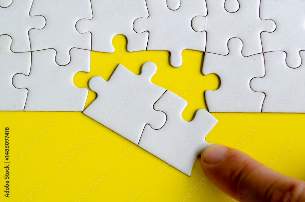 Fototapeta premium Hand placing missing jigsaw puzzles. A simple yet powerful concept of puzzle parts representing solutions unity and purposeful connection