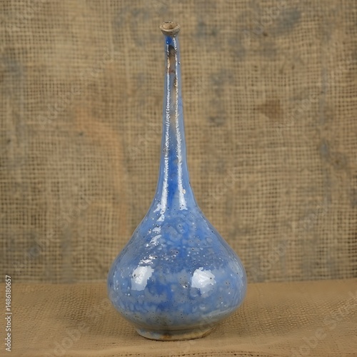 Handmade blue ceramic vase with tall neck against a rustic burlap backdrop