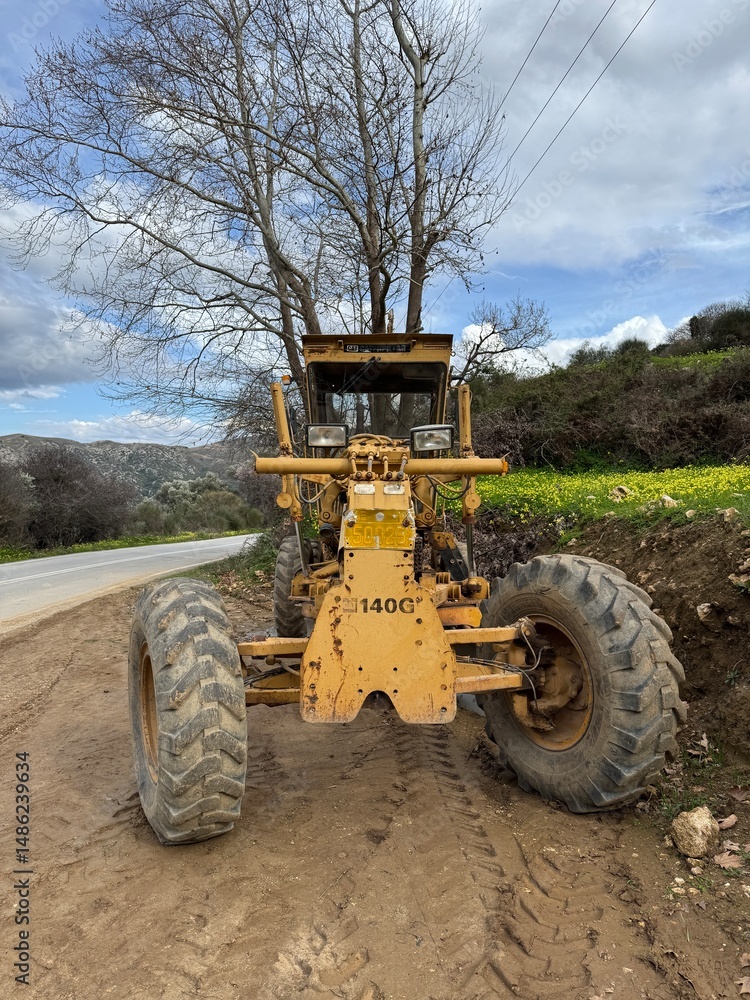 Obraz premium An old yellow construction tractor left abandoned and weathered by time, showing signs of rust and decay — a silent relic of past industrial activity. 