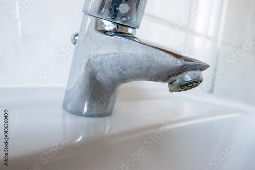 Metal tap with much water  limescale water in bathroom.