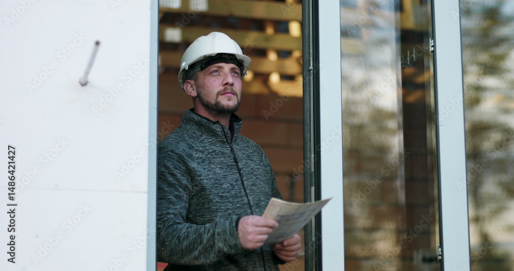 Construction worker studying blueprints in doorway, hard hat on, focused on details of unfinished building project, conveying precision and commitment in construction Construction worker studying blueprints in doorway, hard hat on, focused on details of unfinished building project, conveying precision and commitment in construction