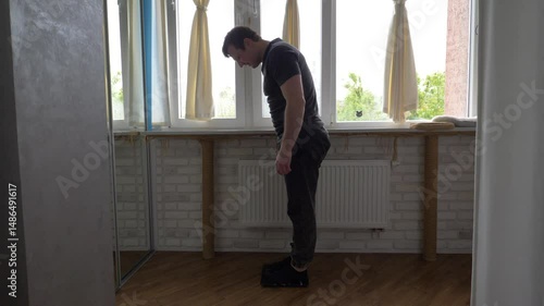 Man at home steps on control scale with feet. Concept of weight loss. Overweight people. Slow motion. Close-up.