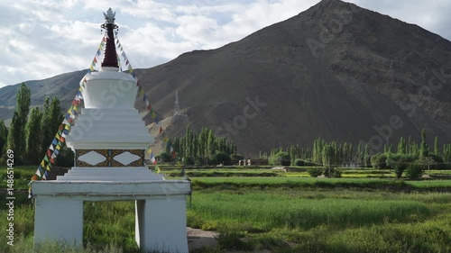 white stupa with buddhist Prayer flags against a mountain in Ladakh