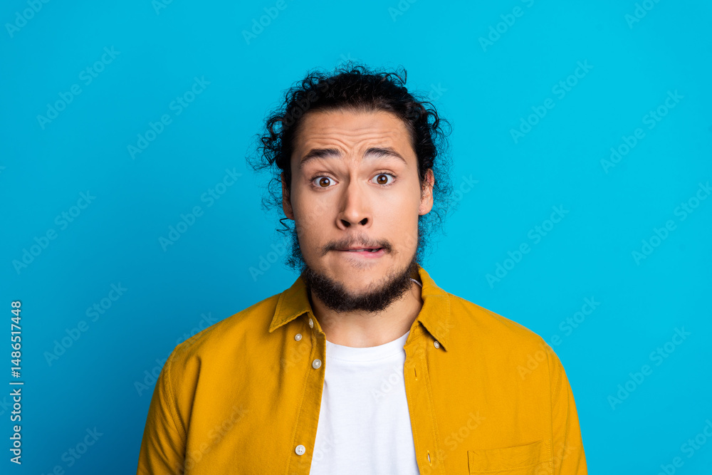 Fototapeta premium Portrait of a trendy man with a surprised expression, wearing a yellow shirt, set against a bright blue background