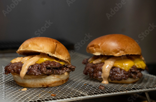 Close-Up of a Juicy Smash Burger with Special Sauce and Melted Cheese on Grill Rack..