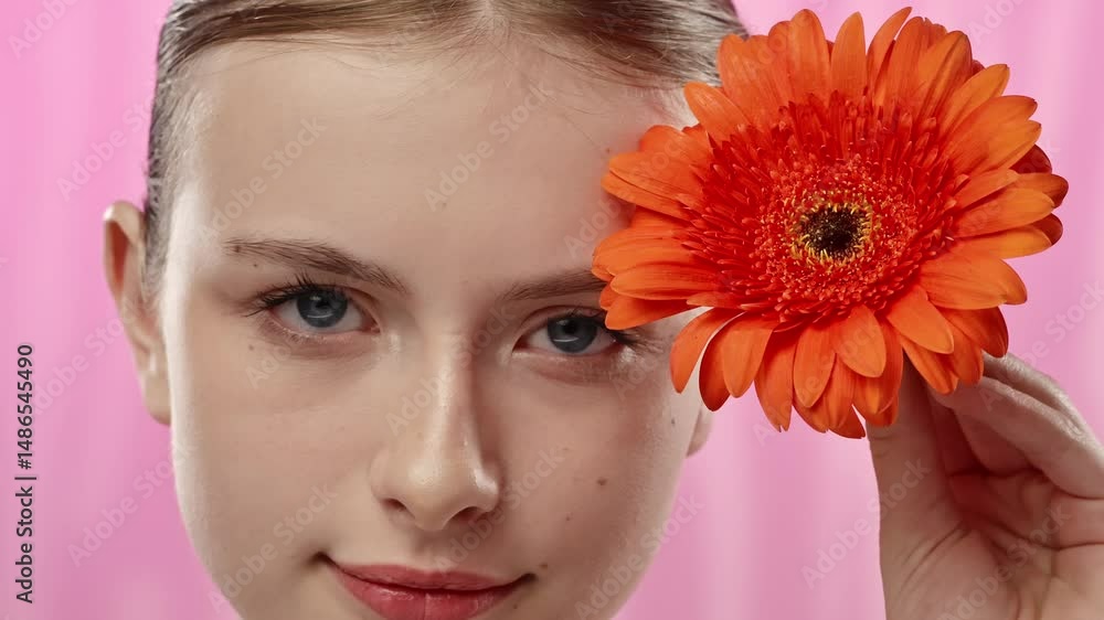 Young Woman with Bright Orange Flower on Vibrant Background Young Woman with Bright Orange Flower on Vibrant Background