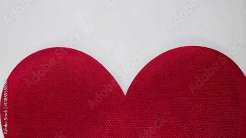 A close up of a red heart shape with a textured surface against a white background in a studio shot