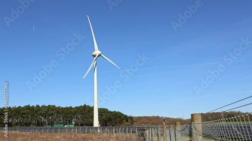 A solitary white wind turbine against a vivid blue sky