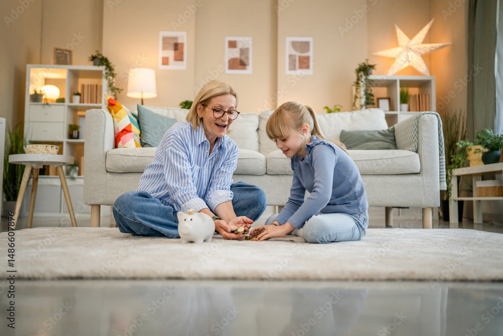 Fototapeta premium grandmother and grandchild save money together at piggy bank