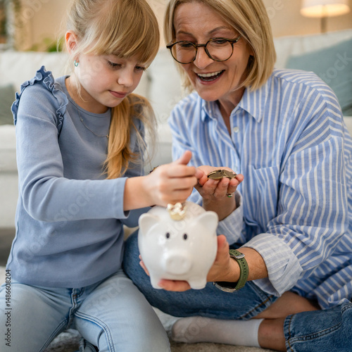 Fotografía grandmother and grandchild save money together at piggy bank