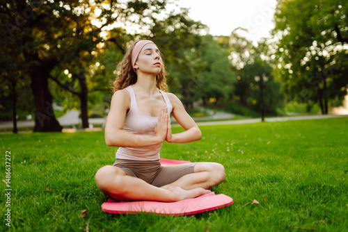 Wallpaper Mural A young woman doing yoga in a park on a mat. A fit woman sitting in a lotus position enjoying the calm and tranquility at sunset. Relaxation concept. Torontodigital.ca