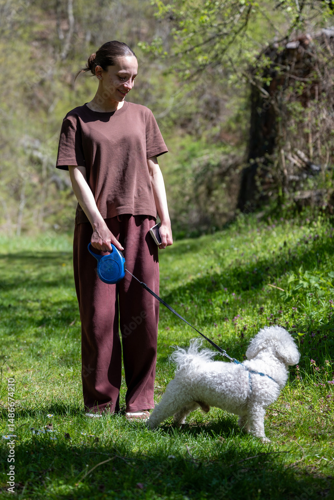 A beautiful young girl enjoys with her White Curly Bison in the forest. the girl is dressed in a brown mother and tracksuit. A young girl plays and sits with her bison in a beautiful forest. A beautiful young girl enjoys with her White Curly Bison in the forest. the girl is dressed in a brown mother and tracksuit. A young girl plays and sits with her bison in a beautiful forest.