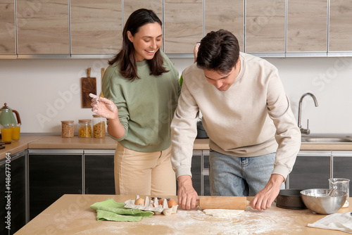 Young couple kneading dough...