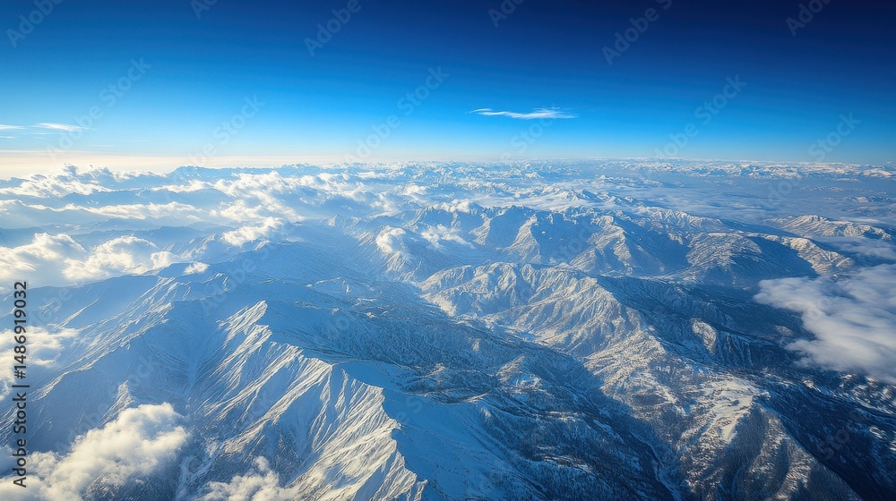Fototapeta premium Aerial View of Snow Covered Mountain Range Under a Clear Blue Sky