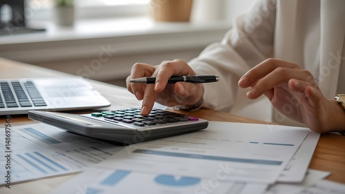 Businesswoman meticulously calculating figures with a calculator in an office setting.