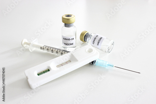 Vial of Covid-19 vaccine, 1 ml plastic syringe with needle and Positive test result of Covid-19 antigen test kit isolated on the white background