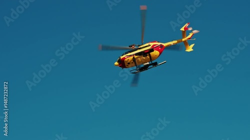 Antibes, France View of a yellow and red emergency helicopter flying on the blue sky
